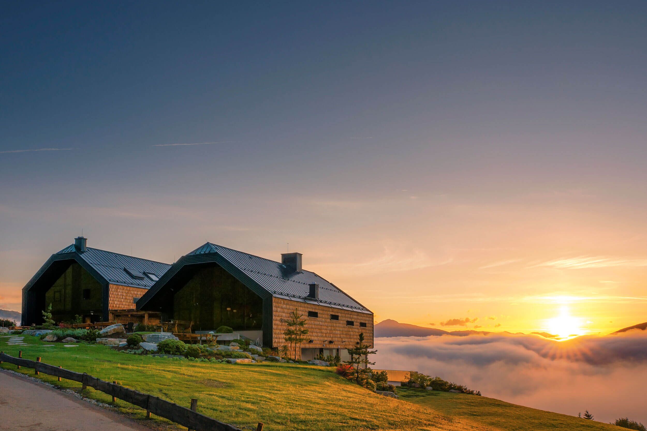 Moderne alpine Architektur mit beeindruckendem Hoteldesign vor einem malerischen Sonnenuntergang über den Bergen.