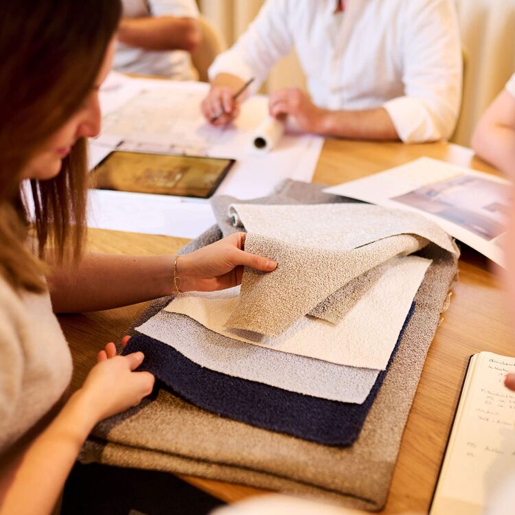 Eine Gruppe plant das Hotelkonzept und wählt Materialien für die Innenarchitektur am Tisch aus.