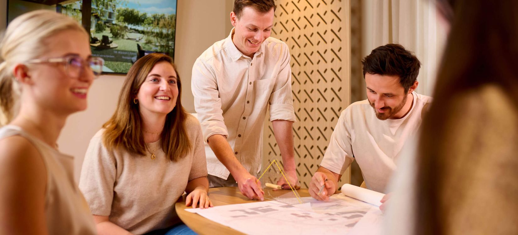 Ein kreatives Team arbeitet an Hotelarchitektur-Entwürfen und bespricht Raumgestaltung für ein neues Hotelkonzept.