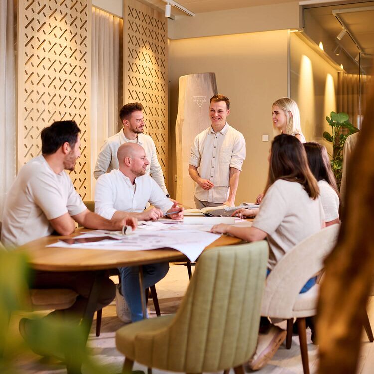 Ein Team diskutiert Hotelarchitektur und Raumgestaltung in einem modernen Besprechungsraum mit natürlichem Licht.