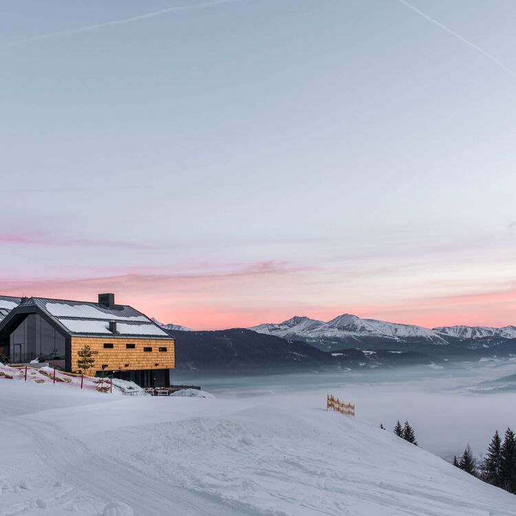 Das moderne Hotel in den Alpen bietet atemberaubende Innenarchitektur mit Blick auf den Sonnenaufgang über dem Tal.