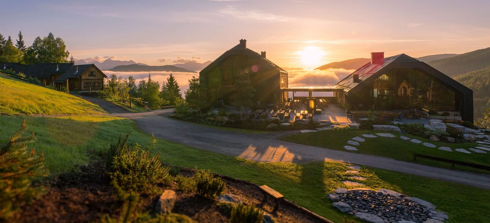 Alpine Architektur zeigt ein Hotel mit atemberaubendem Sonnenuntergang über der Landschaft und einladender Raumgestaltung.