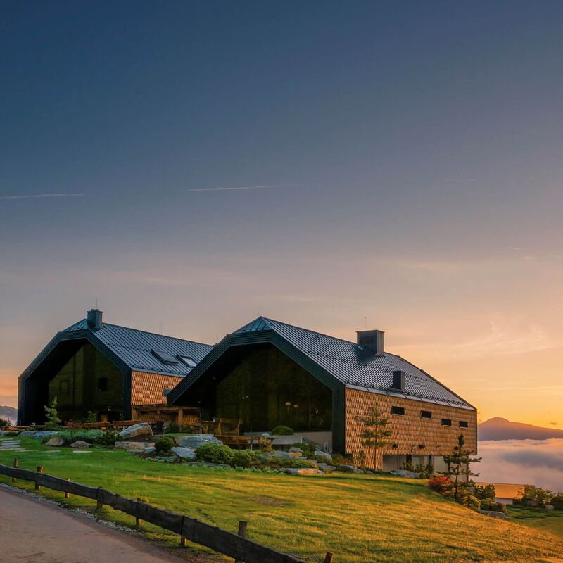 Moderne alpine Architektur mit beeindruckendem Hoteldesign vor einem malerischen Sonnenuntergang über den Bergen.