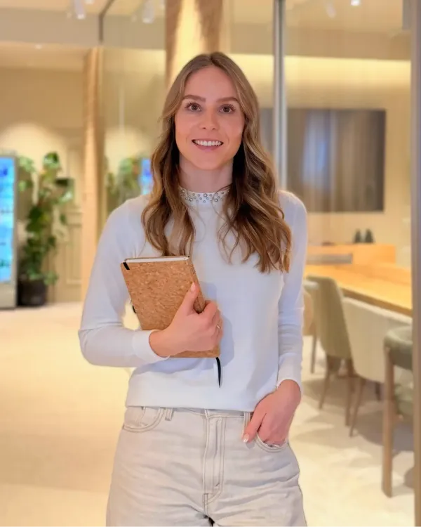 Eine Frau mit Notizbuch steht in einem modernen, hellen Raum, der für Hotelplanung und Innenarchitektur konzipiert ist.