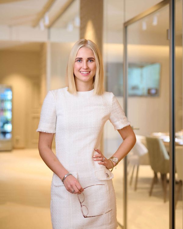 Eine junge Frau steht in einem modernen Empfangsbereich, ideal für Hotelarchitektur und Gästeerlebnis.