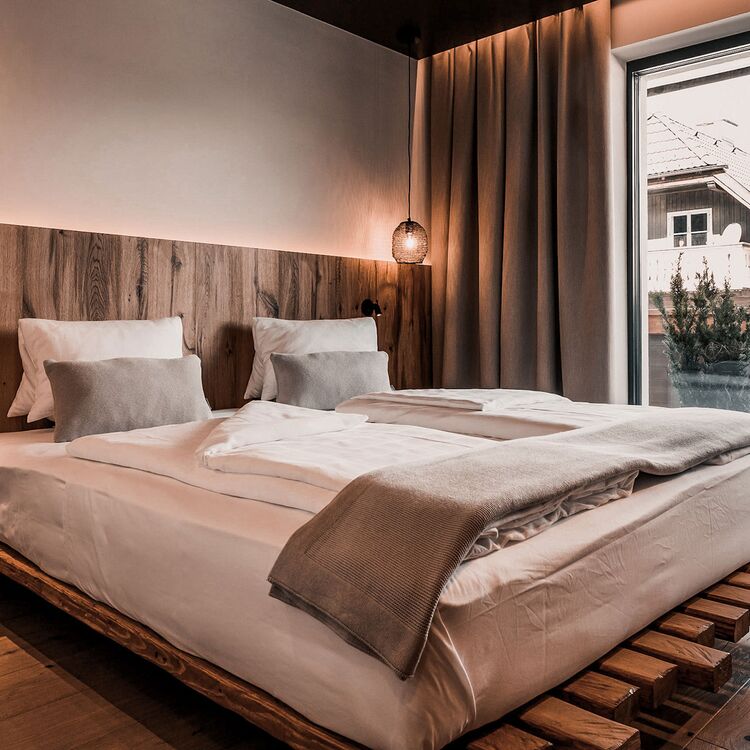 Ein modernes Hotelzimmer mit Holzdetails und Balkon, ideal für ein entspanntes Gästeerlebnis in alpiner Architektur.