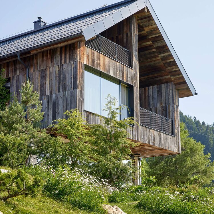 Ein modernes Hotel mit alpine Architektur, umgeben von Natur und grünen Wiesen, bietet Gästen ein einzigartiges Erlebnis.
