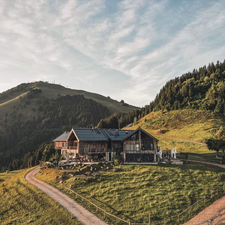 Alpine Architektur präsentiert ein modernes Hotel, umgeben von malerischer Natur und sanften Hügeln.