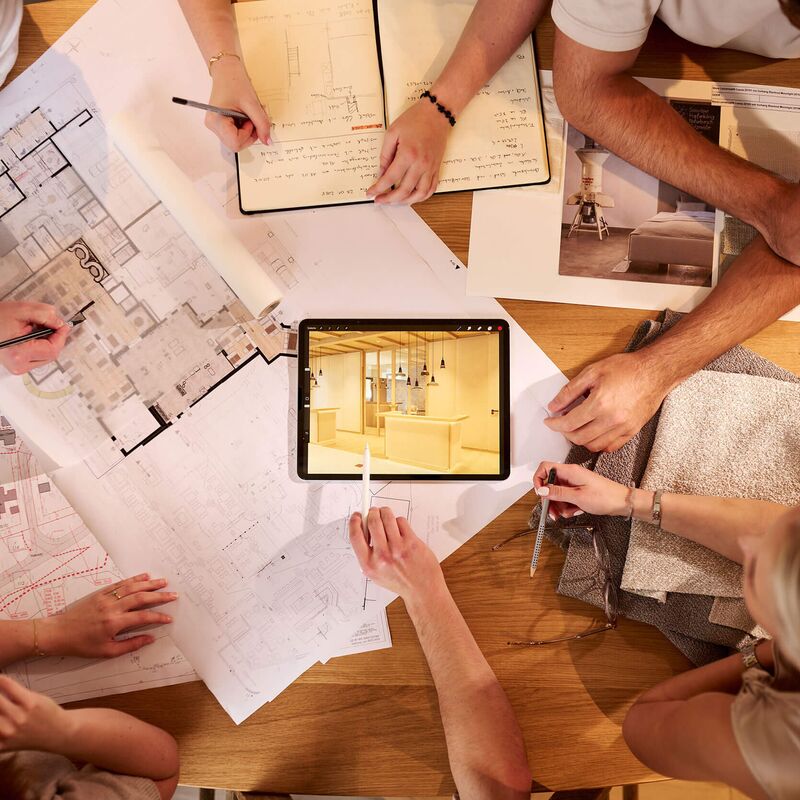 Hotelplanung bei ecoTECTURA: Grundrisse, Materialproben und Tablet auf dem Besprechungstisch