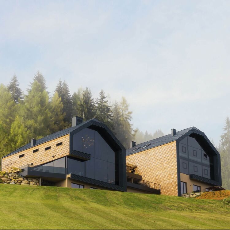Modernes Hotelgebäude in alpiner Architektur, umgeben von Bäumen und Wiesen, ideal für ein einzigartiges Gästeerlebnis.