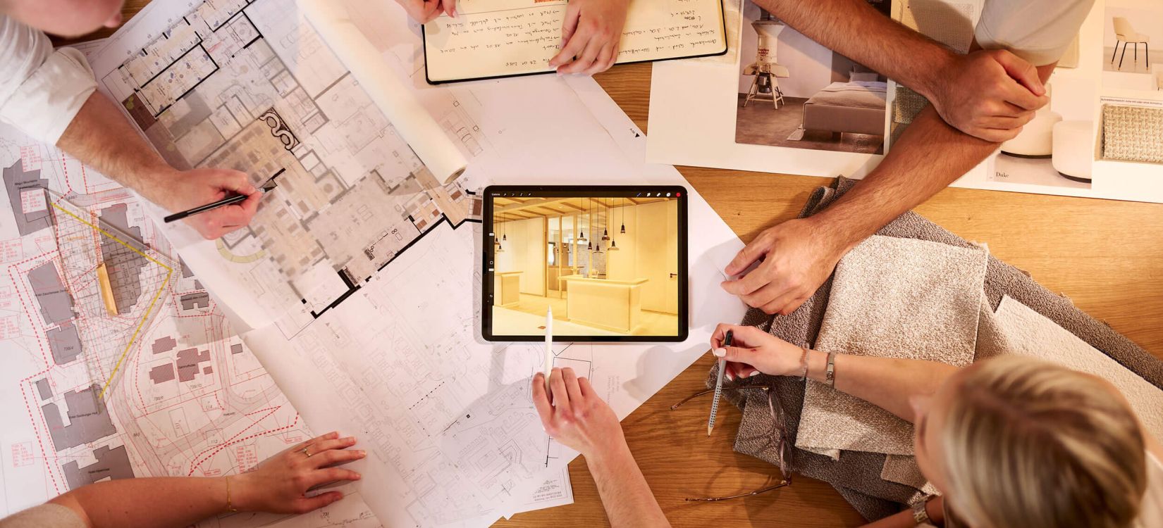 Fachleute planen Hotelarchitektur und Raumgestaltung mit Plänen und Materialien bei einem kreativen Meeting.