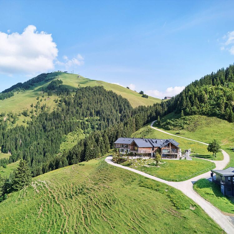 Ein modernes Hotel in alpiner Architektur bietet Gästen beeindruckende Ausblicke auf die umliegenden Berge und Wälder.