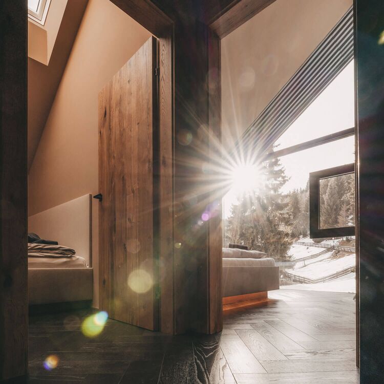 Ein lichtdurchfluteter Raum zeigt moderne Hotelarchitektur mit Holzdetails und Blick auf die alpine Landschaft.