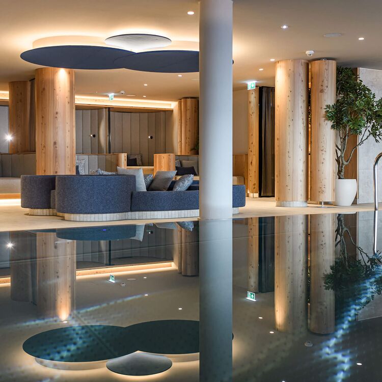 Moderne Hotelarchitektur mit eleganter Raumgestaltung und stilvollen Sitzbereichen im reflektierenden Poolbereich.