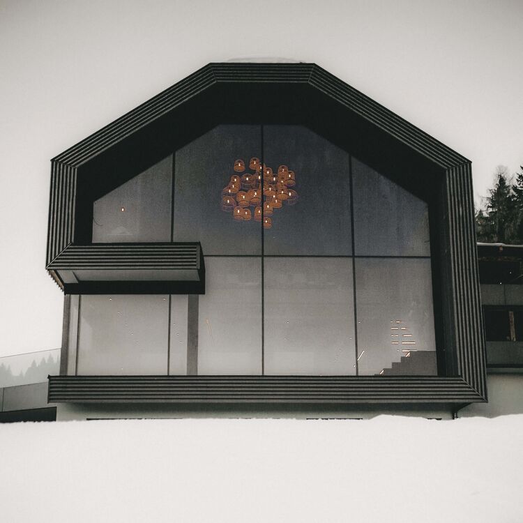 Moderne Hotelarchitektur mit großflächigen Fenstern und einzigartigem Design in alpiner Umgebung.