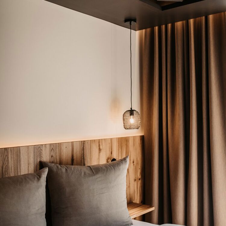 Modernes Schlafzimmer mit Holzdetails und sanfter Beleuchtung, ideal für Hotelarchitektur und Gästeerlebnis.