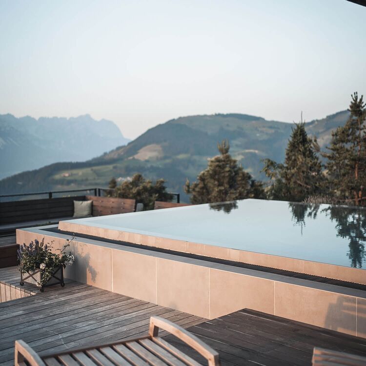 Der Infinity-Pool mit Bergblick ist ein Beispiel für moderne Hotelarchitektur und Raumgestaltung im alpinen Stil.
