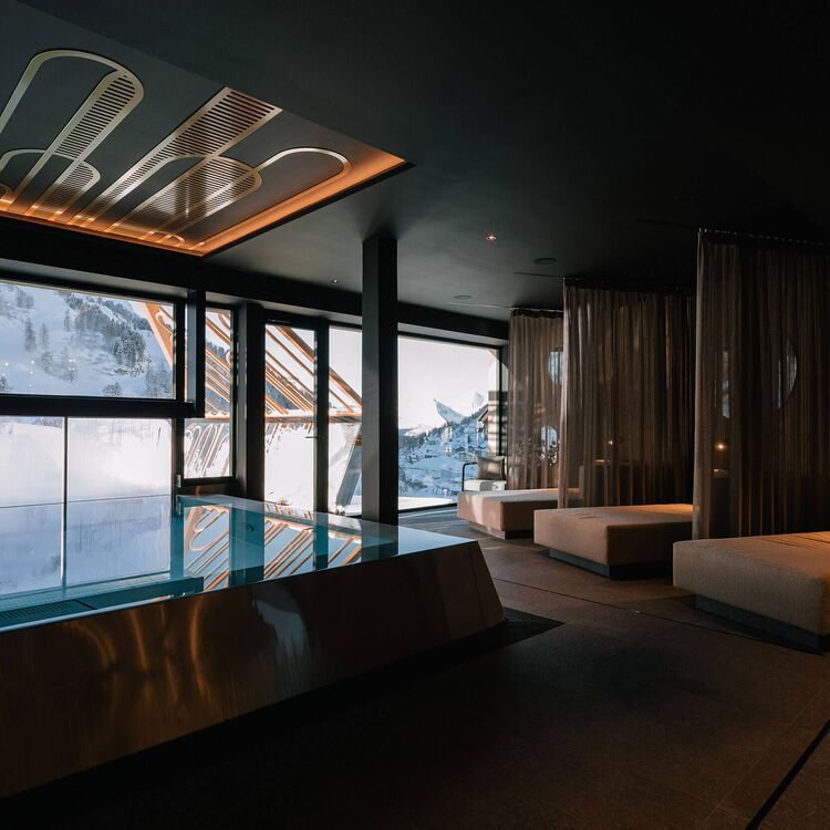 Luxuriöse Hotelarchitektur mit eleganter Innenarchitektur und Blick auf die alpine Landschaft durch große Fenster.