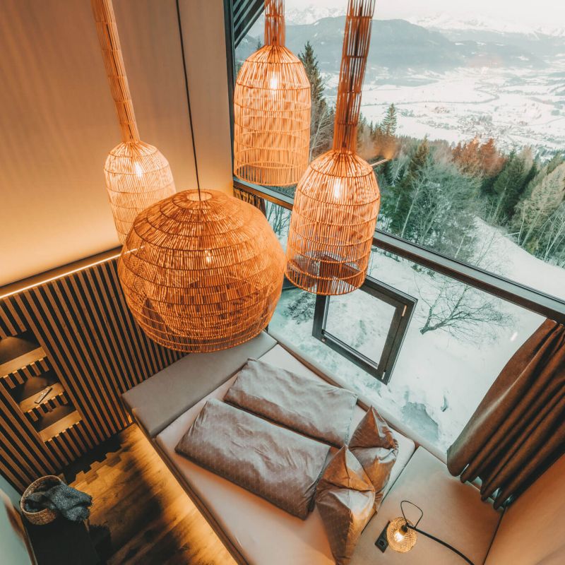 Modernes Hotelzimmer mit alpiner Architektur, großen Fenstern und gemütlicher Atmosphäre für ein besonderes Gästeerlebnis.