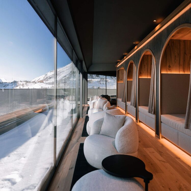 Moderne Hotelarchitektur mit gemütlichen Sitzbereichen und Blick auf die alpine Landschaft in einem eleganten Raumdesign.