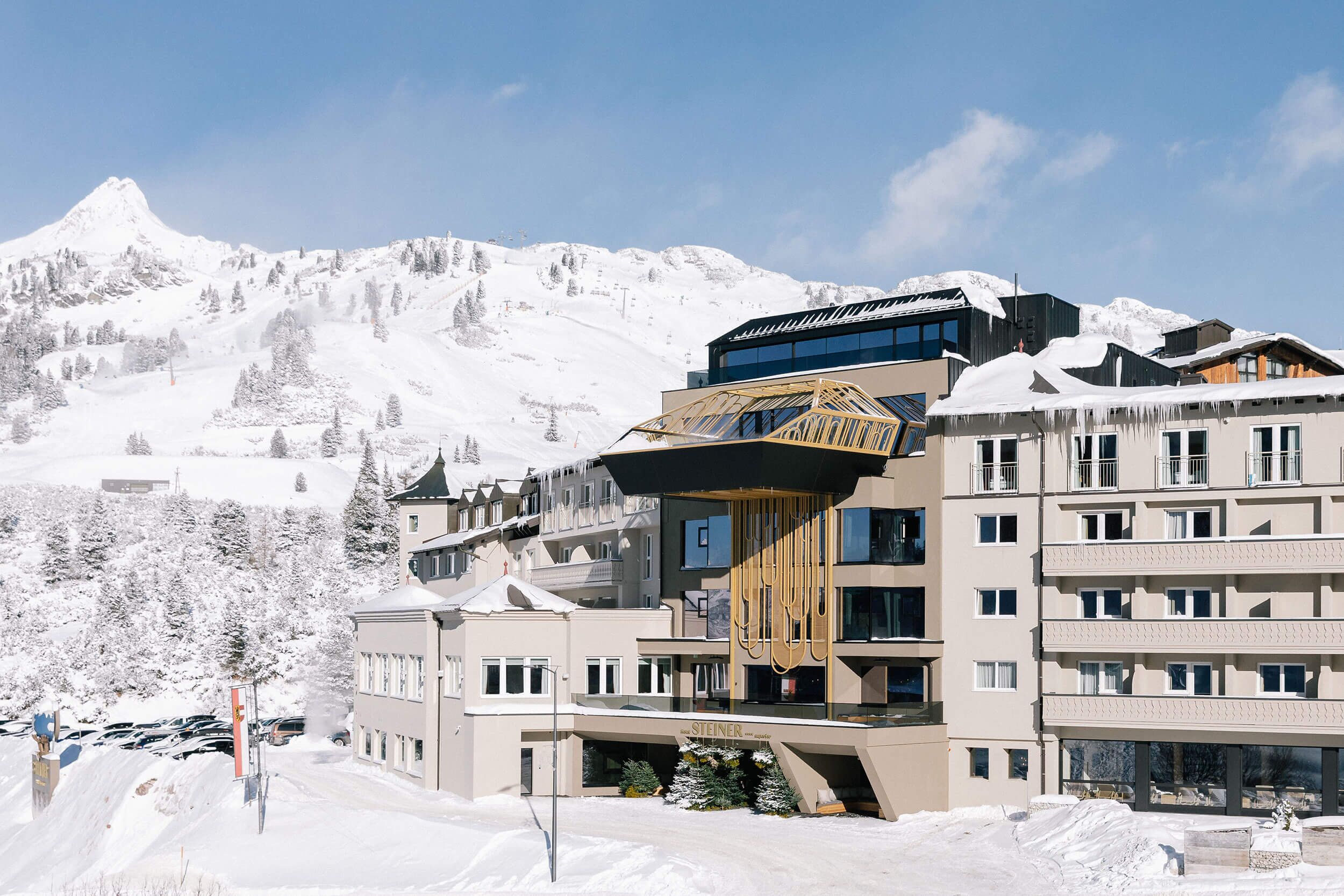 Moderne Hotelarchitektur in den Alpen, umgeben von schneebedeckten Bergen und ideal für ein einzigartiges Gästeerlebnis.