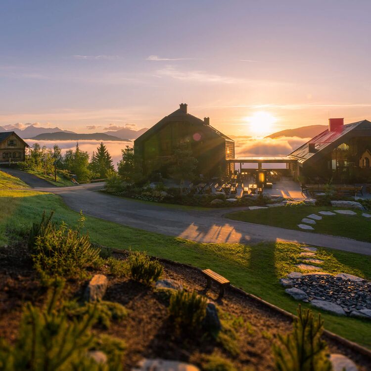 Alpine Architektur zeigt ein Hotel mit atemberaubendem Sonnenuntergang über der Landschaft und einladender Raumgestaltung.